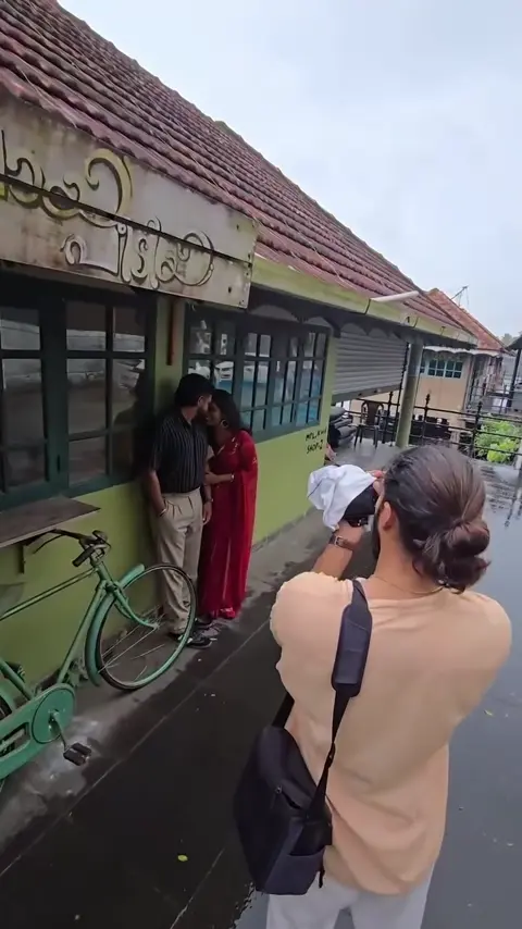 A photographer capturing a couple beside a traditional building