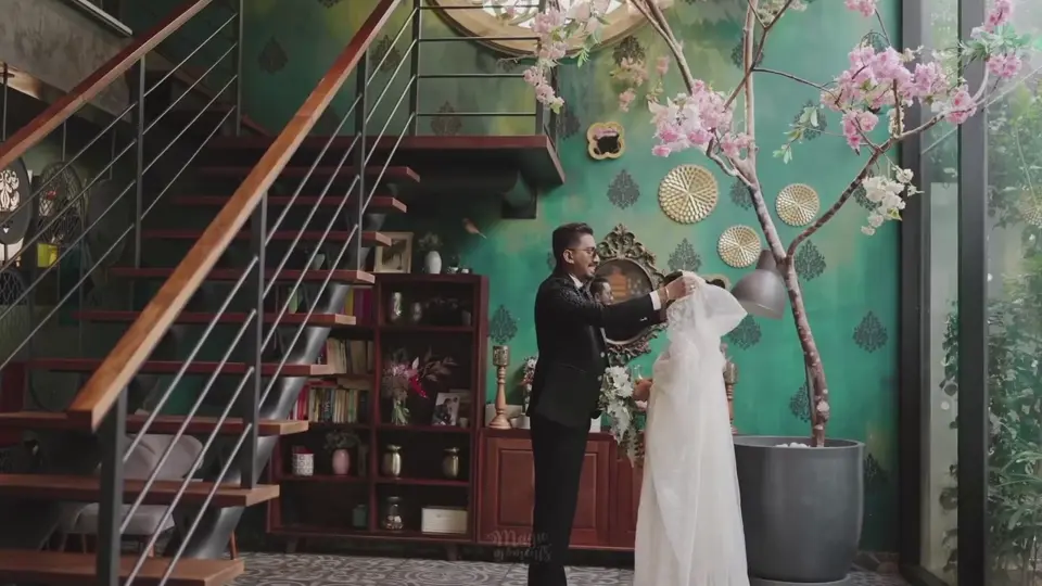 A wedding couple together inside a green café with flowers and a staircase