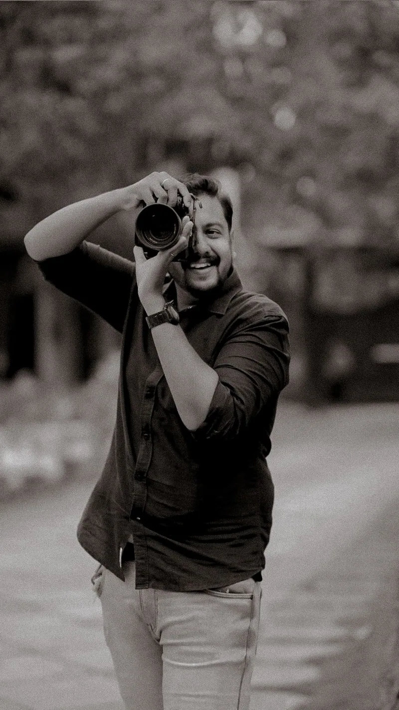 A smiling photographer holding a camera to his eye