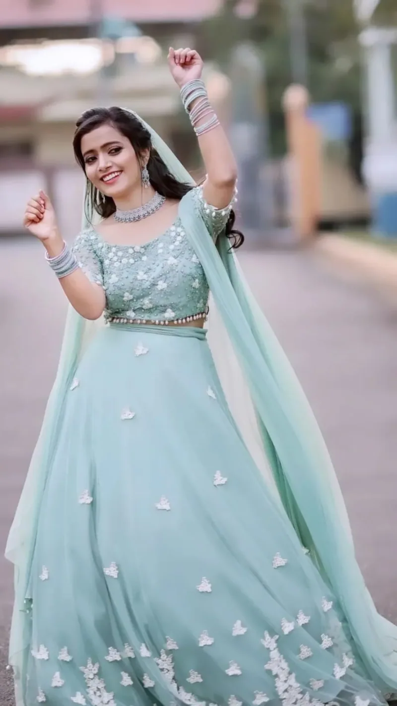 A laughing bride in a mint green outfit lifting her hands