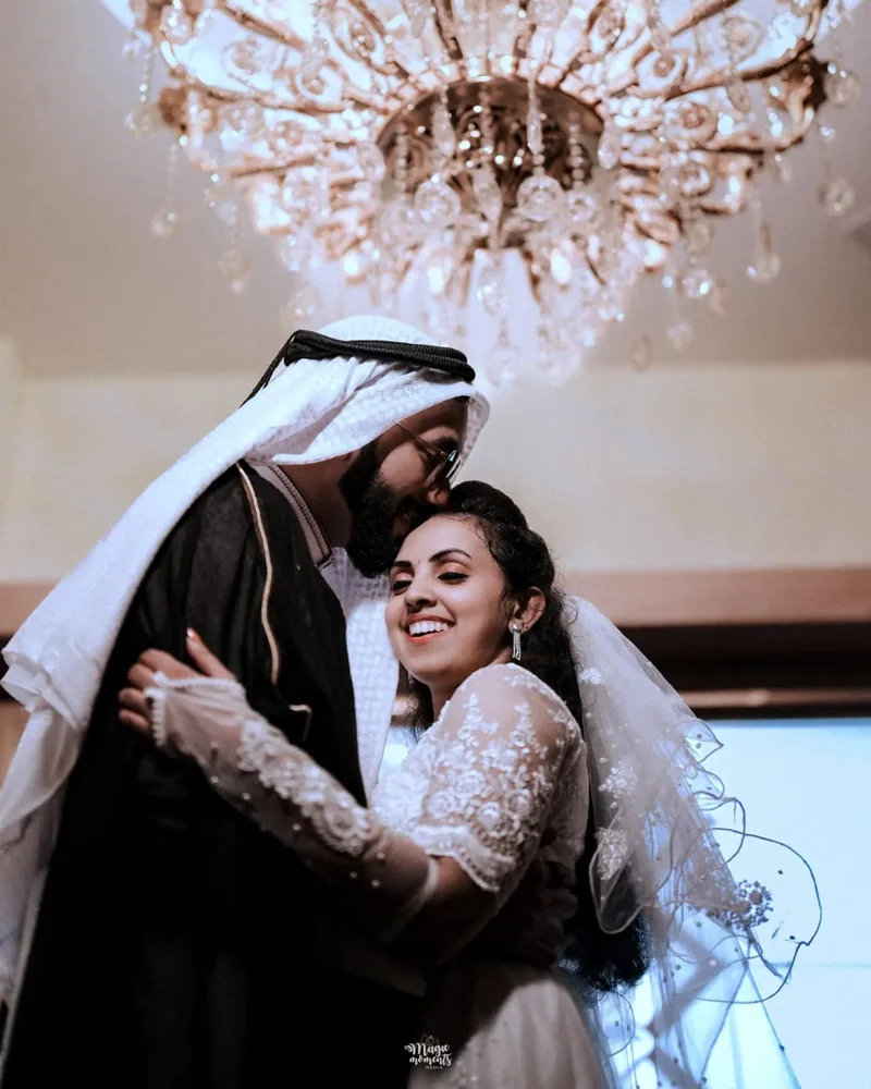A wedding couple embracing beneath a chandelier
