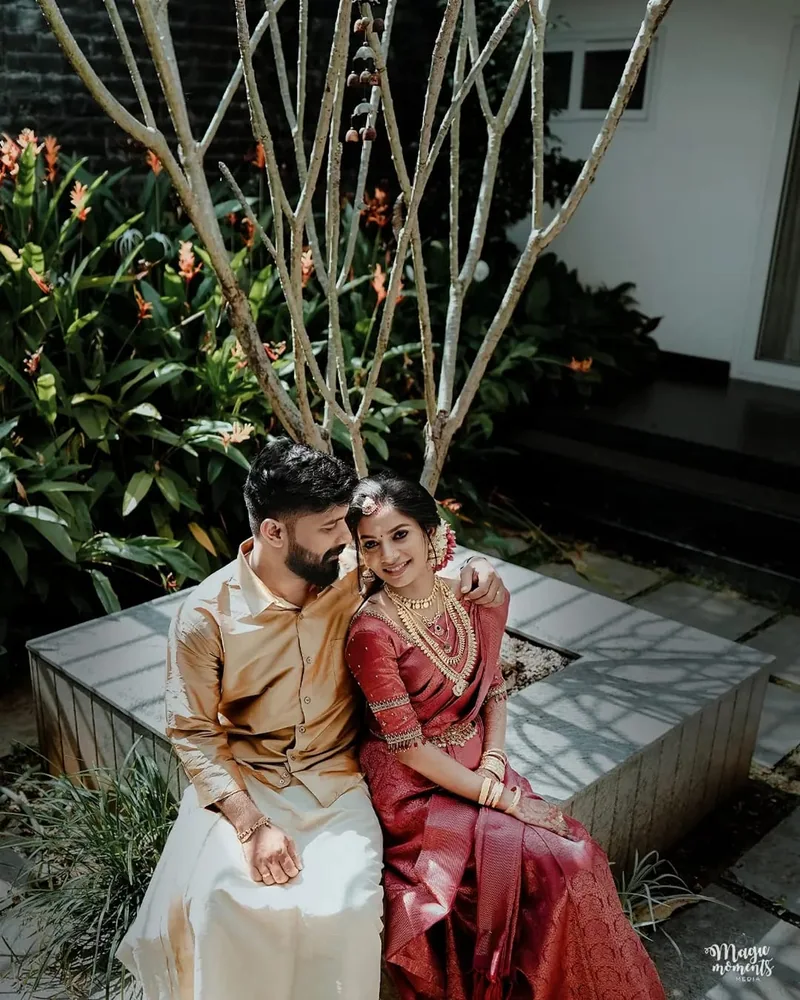 A couple in traditional wedding attire sitting close in a garden