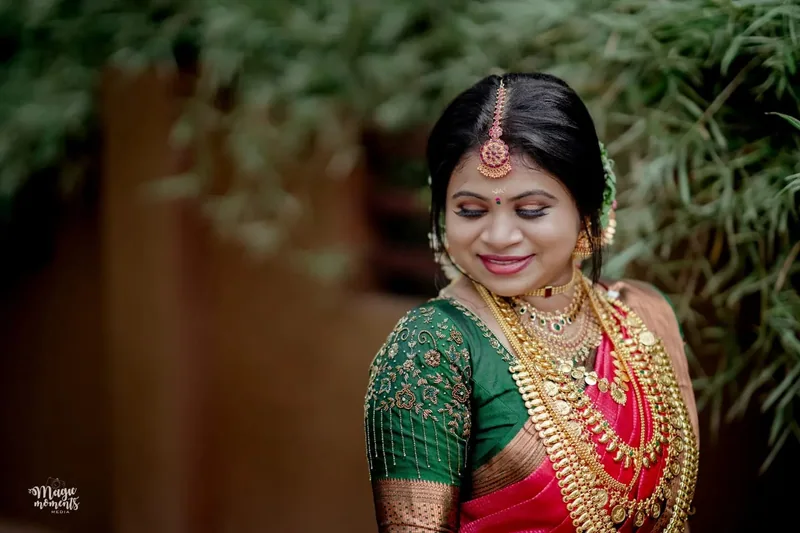 A bride in a green and pink sari looking over her shoulder