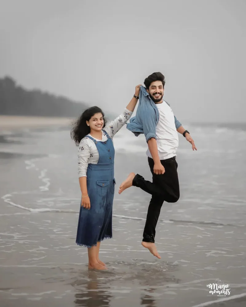 A laughing couple splashing through shallow water at the beach