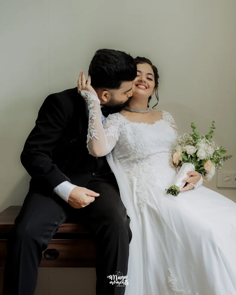 A groom kissing a smiling bride holding a bouquet