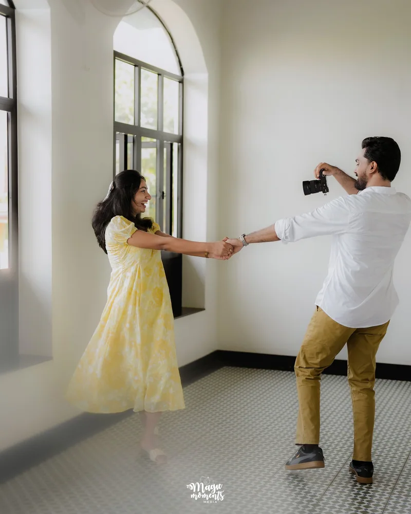 A couple holding hands and dancing beside an arched window